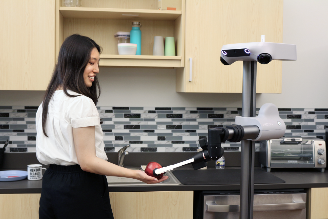 A robot handing an apple to a woman